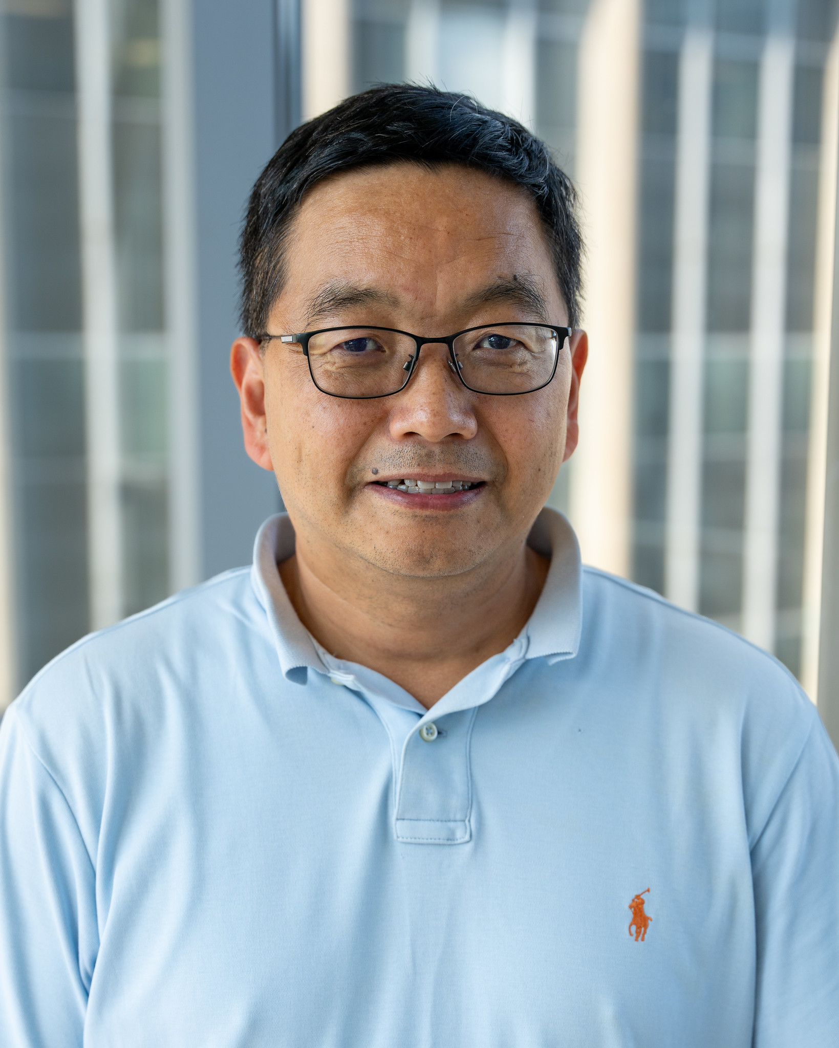 Xuefei Huang poses for a headshot. He wears a light blue polo.